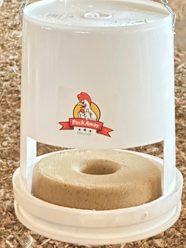 A white feeder with a stone-like circular base and a chicken logo.