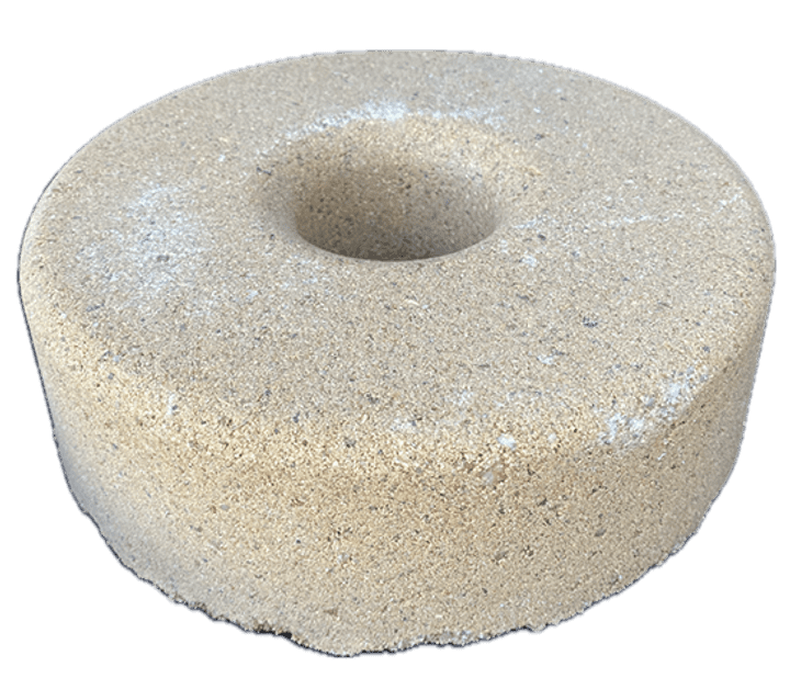 A beige pumice stone shaped like a donut with a rough texture.